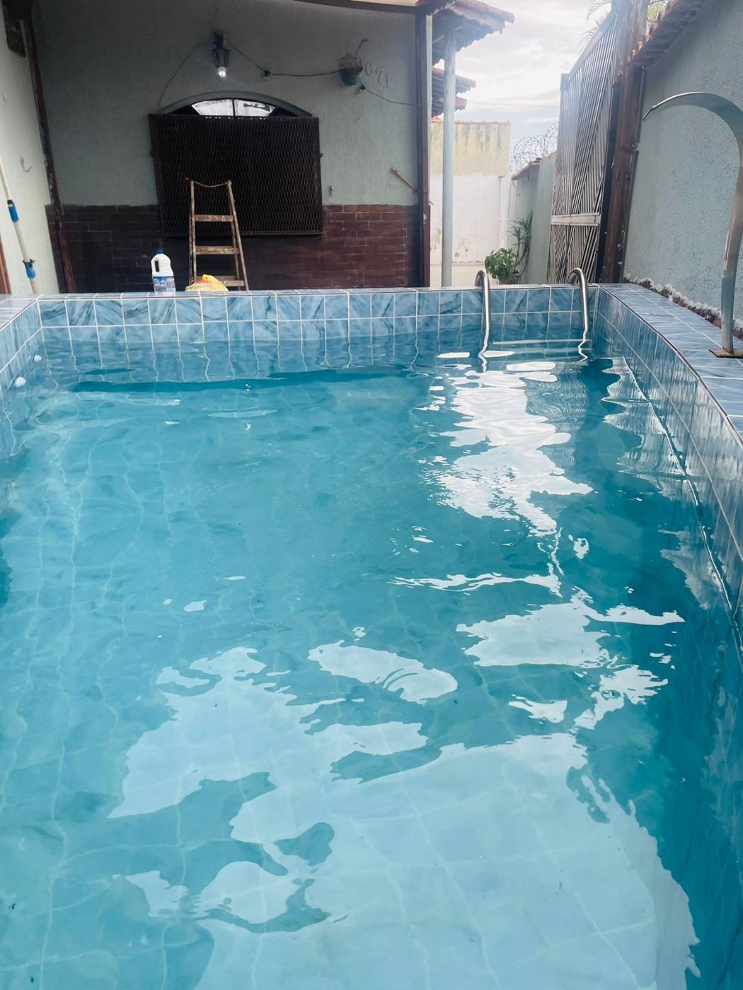 Piscina da casa com cascata, azulejos azuis e água cristalina